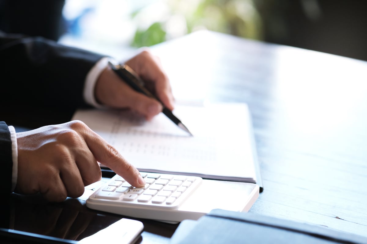 Businessman Analyzing Investment Charts and Pressing Calculator